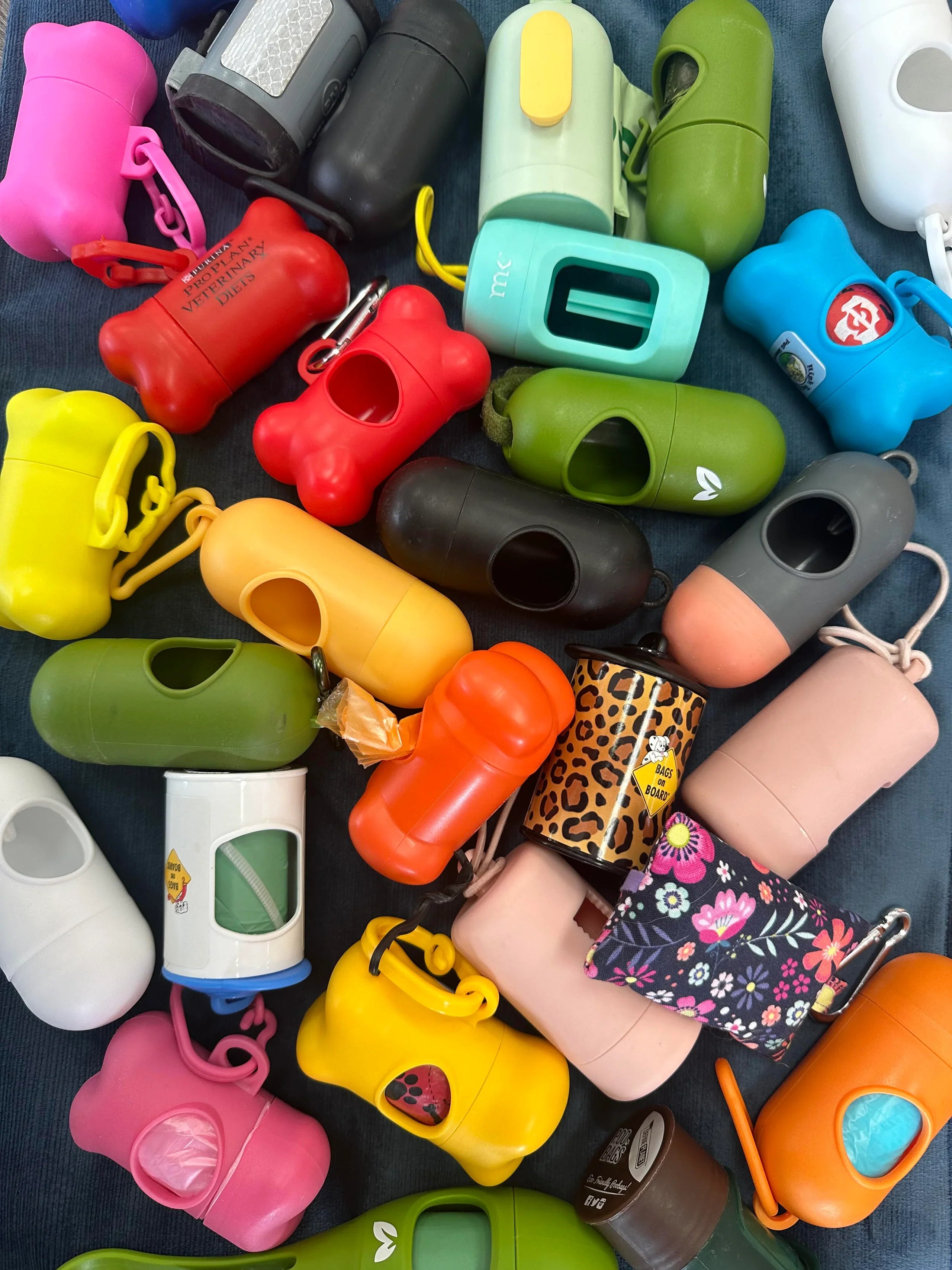 Assorted colorful poop bag holder on a dark surface