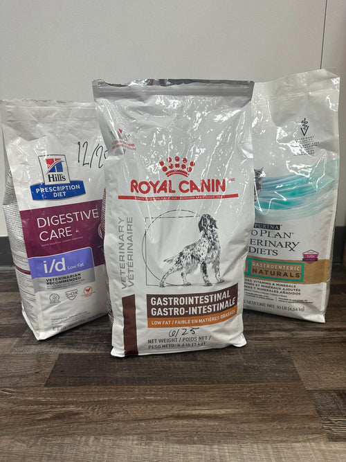 Three bags of Royal Canin veterinary diet products on a wooden surface.